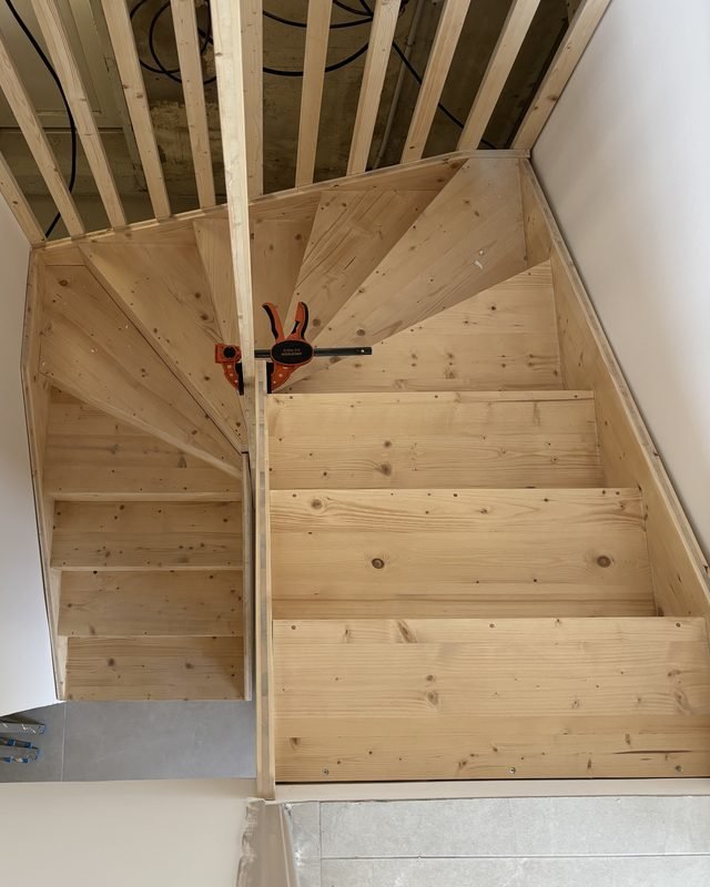 Escalier double quart tournant en bois massif vu d'en haut, fabriqué et posé par Articréa
