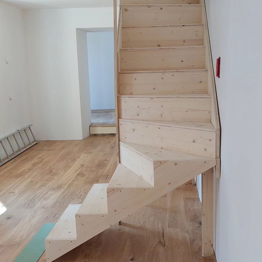 Escalier quart tournant en bois clair posé dans une maison neuve