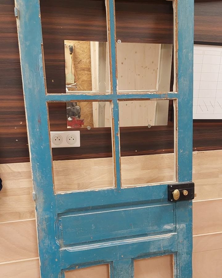 Ancienne porte vitrée en bois peinte en bleu, en cours de restauration à l'atelier